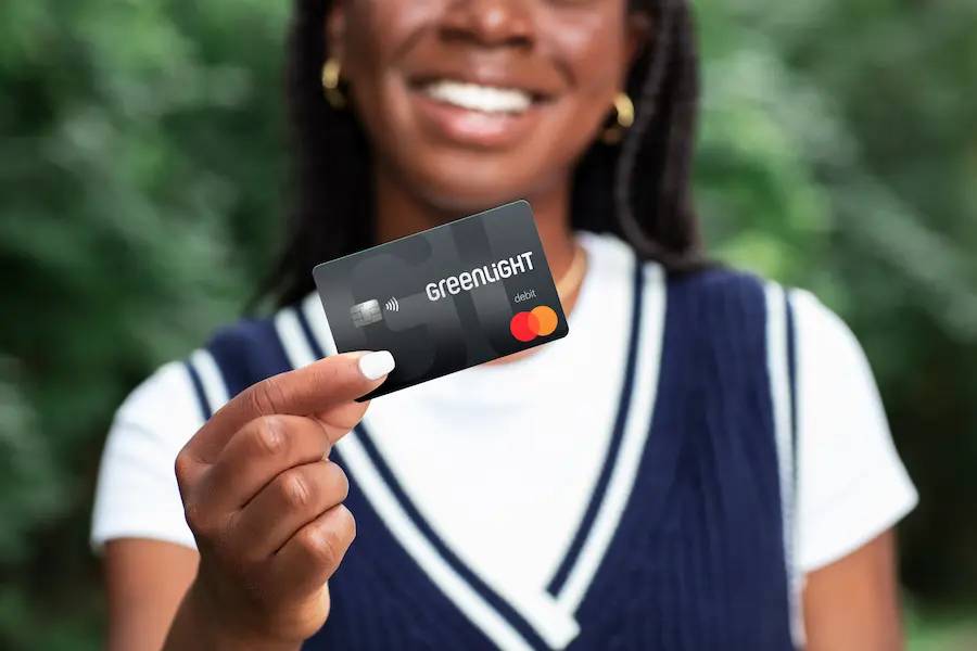 Girl holding out greenlight debit card for kids.