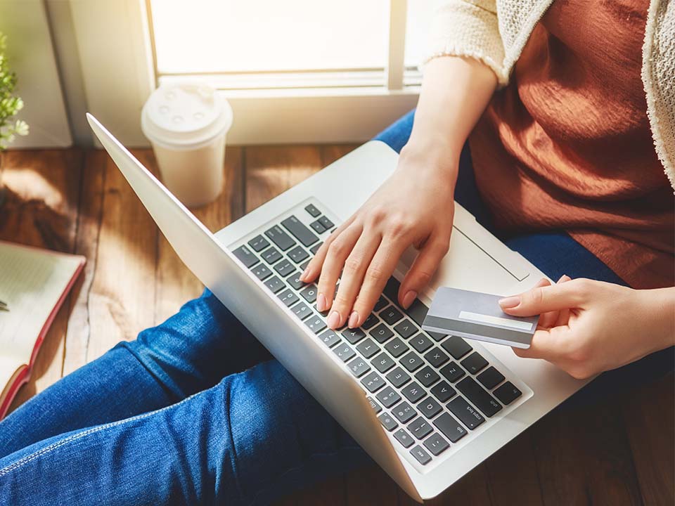 Woman on laptop with credit card in hand