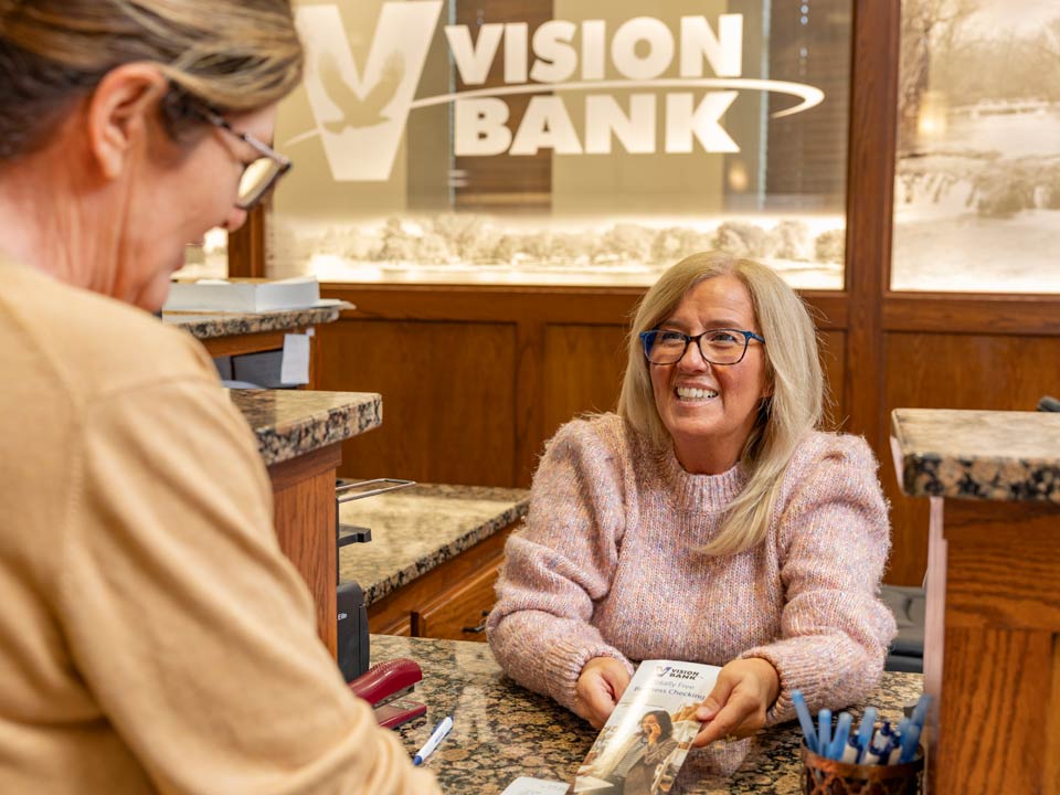 Vision Bank employee helping customer at teller line