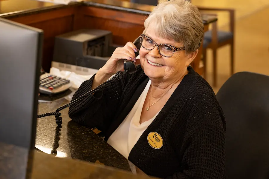 Vision Bank employee in Shawnee smiling holding a phone up to her ear.